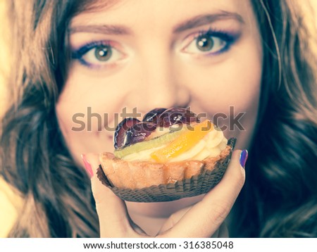 Bakery sweet food and people concept. Closeup woman face open wide eyes and fruit cake in mouth