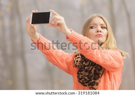 Happy fashion woman in fall autumn park taking selfie self photo picture. Pretty joyful girl photographing.