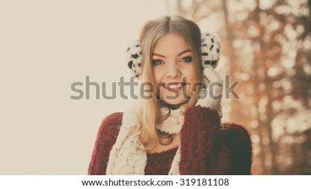 Portrait of pretty smiling fashionable woman in fall forest park. Happy gorgeous young girl in earmuffs and sweater pullover. Autumn winter fashion. Instagram filter.