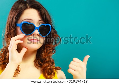 Summer fashion eyes protection concept. Closeup girl long curly hair in blue heart shaped sunglasses making thumb up hand sign gesture