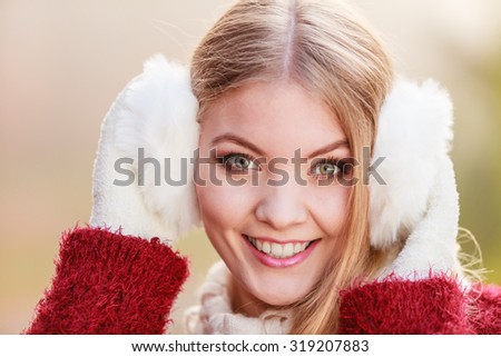 Portrait of pretty smiling fashionable woman in fall forest park. Happy gorgeous young girl in white earmuffs and sweater pullover. Autumn winter fashion.