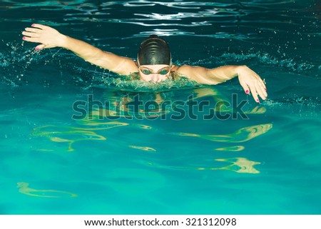 Woman athlete swimming in pool. Active human swimmer taking breath. Water sport comptetition.