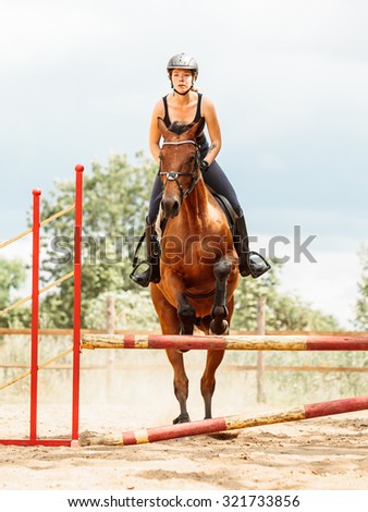 Active woman girl jockey training riding horse jumping over fence. Equestrian sport competition and activity.