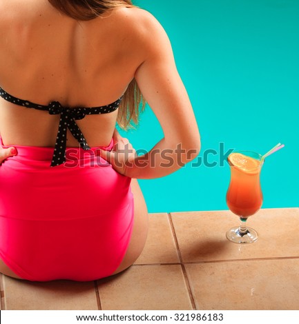 Relax, rest and recreation. Tropical drink and woman back in pink bikini on pool.