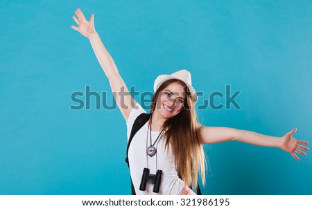 Summer happiness and tourism concept. Young woman in straw hat with backpack spreading hands with joy, happy successful girl with arms up on blue