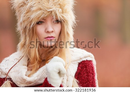 Portrait of pretty fashionable woman in fall forest park. Gorgeous young girl in fur winter hat and sweater pullover. Autumn fashion.