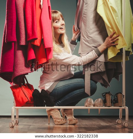 Pretty woman choosing clothes to wear in wardrobe. Attractive young girl customer shopping in mall shop. Fashion clothing sale concept.