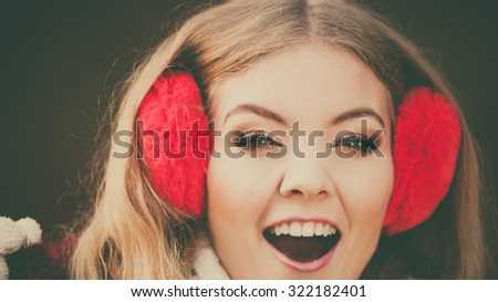 Portrait of pretty smiling fashionable woman in fall forest park. Happy gorgeous young girl in red earmuffs. Autumn winter fashion.