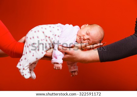 Parenting family and love concept. one month old baby girl sleeping in the comfort of parents arms, red background