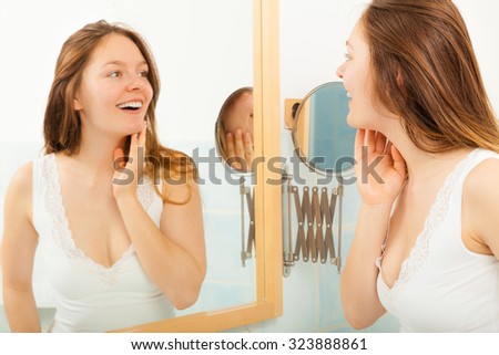Happy young girl woman without makeup in bathroom standing in front of mirror smiling. Natural beauty. Purity.
