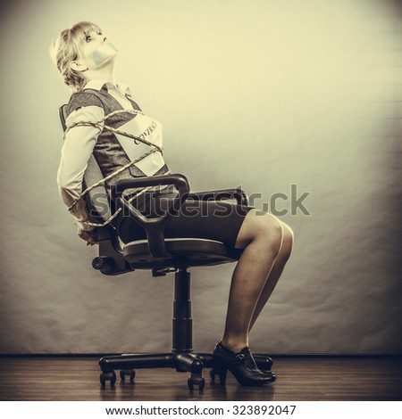 Afraid businesswoman bound by contract terms and conditions with mouth taped shut. Scared woman tied to chair become slave. Business and law concept. Instagram filtered.