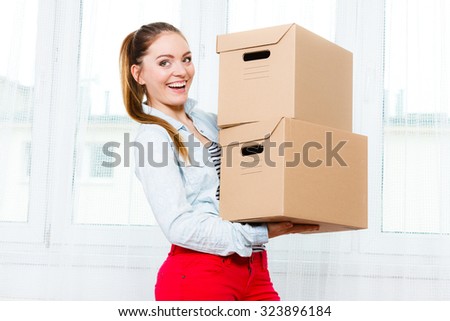 Happy woman moving in carrying cartons boxes. Young girl and unpacking at new apartment house home.