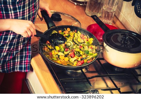 Closeup of human in kitchen cooking stir fry frozen vegetables. Person frying making delicious dinner food meal. Instagram filtered.
