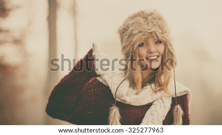 Pretty woman in fall forest park. Gorgeous young girl in fur winter hat and sweater. Autumn fashion.