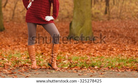 Closeup of woman legs in brown boots. Girl in autumn park forest. Fall winter fashion.