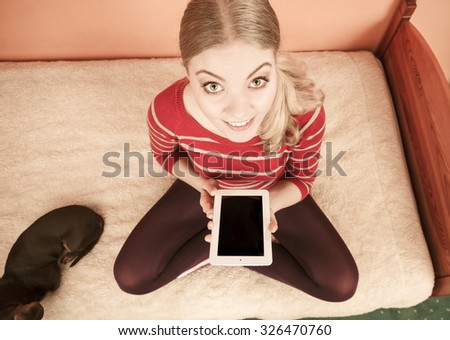 Young woman with dog using computer tablet browsing internet. Girl holding ebook. Technology leisure. High angle view.
