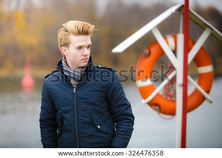 Young handsome man fashion model casual style hair styling outdoor against a marine harbour