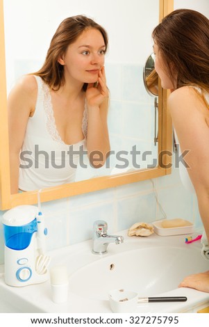 Young girl woman without makeup in bathroom looking in mirror. Natural beauty. Purity.