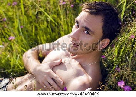 nice guy lying in the meadow among the flowers under the summer sun
