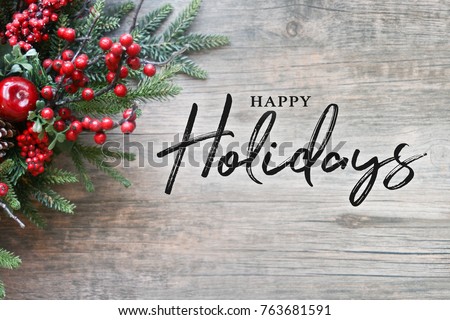 Photo of Happy Holidays Text with Christmas Evergreen Branches and Berries in Corner Over Rustic Wooden Background