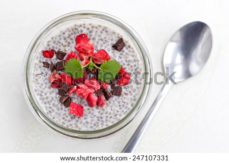 Jar with vanilla chia pudding topped with freeze dried strawberries and dark chocolate