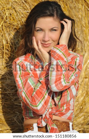 Portrait of young beautiful women near haystack in the field on sunrise