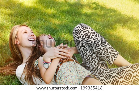 happy little girl and her mother having fun outdoors on the green grass in sunny summer day