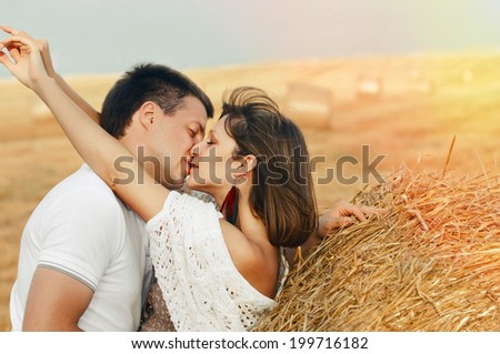 affectionate sensual beautiful romantic couple in love kissing outdoor in summer windy weather field