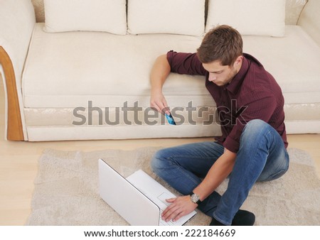 attractive young man buying online by credit card while sitting on the sofa at home, credit business concept