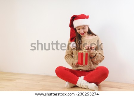 beautiful young woman in santa hat with present box in hands for Christmas or New Year holiday on white background