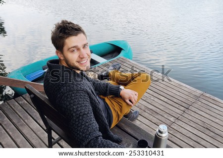 handsome attractive man on the wooden pier at the lake on beautiful nature background, relax concept