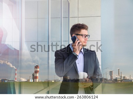 double exposure of urban attractive businessman with phone device and industrial enterprise building background