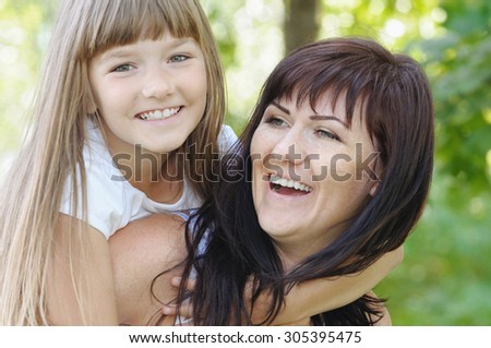 happy girl and her mother having fun in the park outdoors in sunny summer day, happy family concept