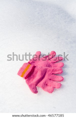 Warm female pink gloves on fresh snow in winter.