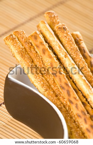 Salty sesame sticks in dish and on table cover.