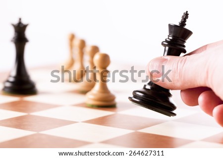 Playing chess game - a hand moving the black king with white pawns in perspective