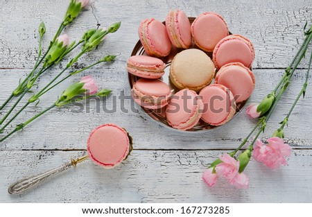 Pink macaroon with pink carnations on a white wooden table