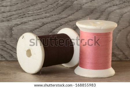 Close up of colored spools of cotton threads on wooden surface and background