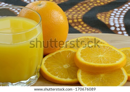 Close up of one fresh orange with some sliced oranges and a glass of orange juice