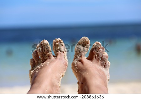girls feet in the sand on the background of the ocean