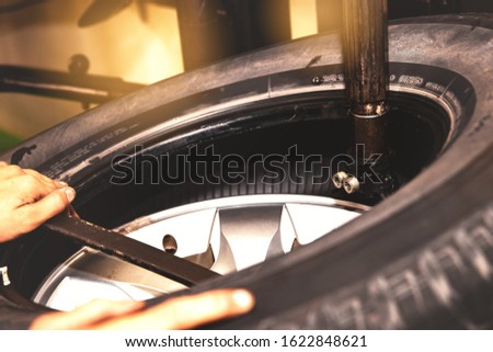
Concept of changing tires for safer driving : Closeup of a professional mechanic, remove tire rims using modern tools in the car service station. Stock fotó © 