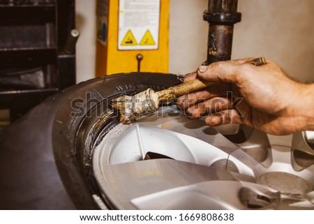 The mechanic's hands in the automobile service center use a heat-resistant grease brush, rubber rim, assembled together to prevent damage and friction between the black tire rim and alloy wheels.
 Stock fotó © 