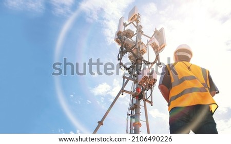 Helmeted asian male engineer works in the field with a telecommunication tower that controls cellular electrical installations to inspect and maintain 5G networks installed on high-rise buildings. Foto stock © 