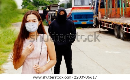 Young woman hygienic mask walks alone being careful to protect herself when she learns that she is being driven by a black robed man walking behind him to rob valuables : Crime concept
 Foto stock © 