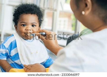 Similar – Image, Stock Photo Cheerful mother feeding adorable baby