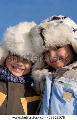 Cute girl and boy winter portrait in the fur-cap