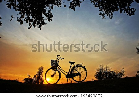 Beautiful landscape of nature with impression of the sun  and silhouette of bicycle  in sunrise at countryside