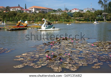 DA LAT, VIET NAM- DEC 27: Recreation of traveller by ride duck boat on lake, tranquil landscape of romantic lake with lotus flower on surface water in Da Lat, Vietnam on Dec 27, 2013