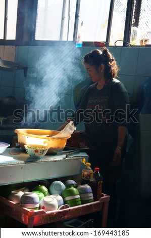 DA LAT, VIET NAM- DEC 28: Chef working at rice restaurant, she broit meat for com tam meal, this is specific of vietnamese food in Dalat, Vietnam on Dec 28, 2013
