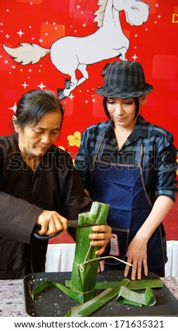 HO CHI MINH CITY, VIET NAM- JAN 15: Singer Phi Nhung make traditional food in competition, the cake cover by green bananna leaf in Ho Chi Minh, Vietnam on Jan 15, 2013